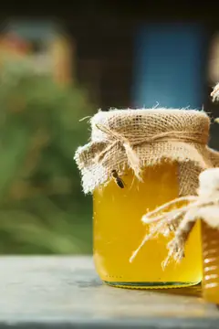 Банка мёда и пчела крупным планом